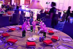 a round table with purple and red napkins, silverware and place settings on it