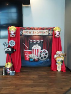 a stage set up with red curtains, popcorn buckets and movie equipment on it