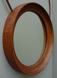 a round mirror hanging on the wall with a cord attached to it's side