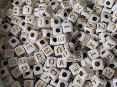 white and gold dices with letters on them are stacked together in a pile to spell out the alphabet