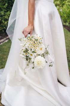 a bride holding a bouquet of white and yellow flowers