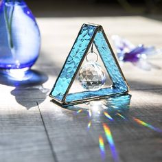 a triangle shaped object sitting on top of a wooden table next to two vases