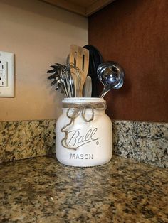 a mason jar with spoons and utensils in it sitting on a counter