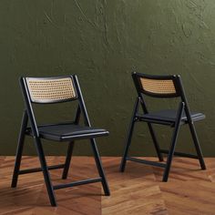 two chairs sitting side by side in front of a green wall and wood flooring