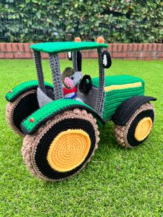 a crocheted toy tractor sitting in the grass