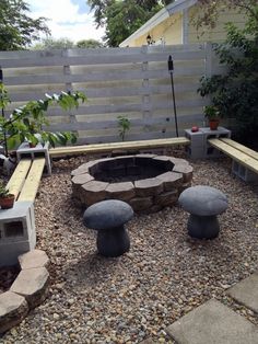 an outdoor fire pit surrounded by gravel and stone benches