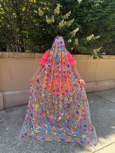 a woman wearing a colorful veil walking down the street with her back to the camera