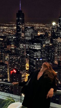 a woman standing on top of a tall building next to a toilet in front of a cityscape