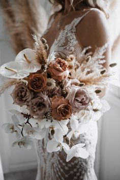 a woman in a wedding dress holding a bouquet of flowers and feathers with her back to the camera