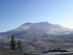 there is a mountain in the distance with snow on it's top and trees below