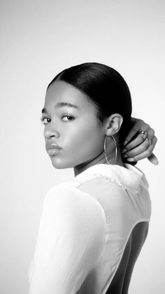 a black and white photo of a woman with her hand on her head, wearing large hoop earrings