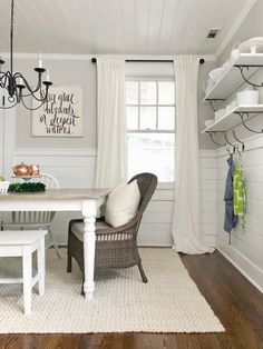 a dining room with white walls and wood flooring, chandelier hanging from the ceiling