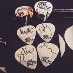 four guitar picks with the words arctic monkeys written on them and some other music memorabilia