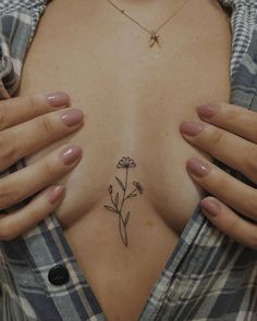 a woman's breast with a small flower tattoo on her left side ribcage