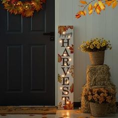 a sign that says happy harvest next to some flowers and pumpkins on the ground