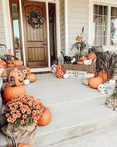 a front porch decorated for halloween with pumpkins and flowers