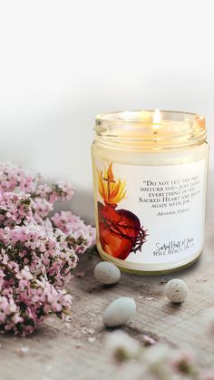 a candle sitting on top of a table next to some flowers and rocks in front of it