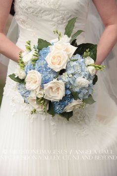 a bride holding a bouquet of white and blue flowers on her wedding day at the same time