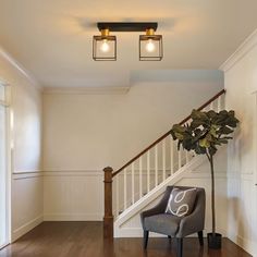 a chair sitting in the middle of a living room next to a stair case with two lights on it