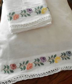 two white linens with embroidered flowers on them