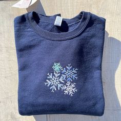 PLEASE READ FULL DESCRPITION Snowflake Crewneck Welcome to ML Blanks Boutique All items in my shop are made by me.... Happy Shopping!! This Snowflake embroidered crew neck sweatshirt is super cute and Trendy!! The Embroidery is done in a 4 different colors of thread on a Navy Crewneck sweatshirt.  Each snowflake is a different  size  Sweatshirts are Unisex, 100% cotton and very soft and cozy. Perfect sweater for cozying up in! NOTE TO BUYER GIFT WRAPPING AVAILABLE  IF THIS A GIFT, YOU HAVE DELIV Christmas Crew Neck Sweatshirt With Embroidered Logo, Winter Sweatshirt With Embroidered Graphics, Embroidered Crew Sweater For Winter, Winter Embroidered Sweatshirt, Christmas Embroidered Crew Neck Sweatshirt, Christmas Crew Neck Sweatshirt With Embroidered Graphics, Winter Cotton Sweater With Custom Embroidery, Winter Crew Neck Sweatshirt With Custom Embroidery, Winter Crew Sweatshirt With Embroidered Logo