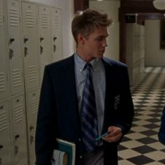 two men in suits and ties standing next to lockers with binders on them