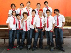 a group of young men standing next to each other in front of a red wall