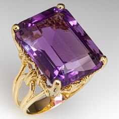 The lovely split shoulder ring features an openwork design and is accented with one (1) emerald cut amethyst weighing approximately 21.57 carats that is set into a four-prong setting. The ring measures 19.9mm at the top, rises 10.6mm above the finger, tapering to 4.0mm wide and 1.2mm thick at the base of the shank. It is currently a size 7. Please note the table facet has some light surface scratches form previous years of wear. Antique Cocktail Ring, Amethyst Cocktail Ring, Amethyst Set, Vintage Cocktail Ring, Golden Ring, Bling Rings, Put A Ring On It, One 1, The Ring