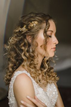 a woman with curly hair wearing a wedding dress and holding her hands on her chest