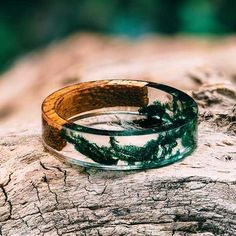 two bracelets sitting on top of a piece of driftwood with trees in the background