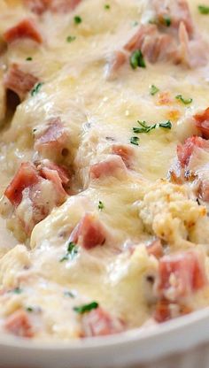 a casserole dish with ham and cheese on top, garnished with parsley