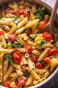 a pan filled with pasta, tomatoes and spinach