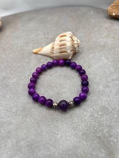 Elevate your style and spirit with this stunning Sugilite and Amethyst gemstone bracelet. Handcrafted with love and care in Port Saint Lucie, Florida, this bracelet features the soothing energies of Sugilite paired with the calming properties of Amethyst. Let this bracelet serve as a reminder of your beachside adventures, with two silver spacers adding a touch of elegance. Whether you're strolling along the shore or attending a special event, this stretch bracelet is the perfect accessory. Harne Adjustable Purple Stretch Bracelet With Natural Stones, Bohemian Purple Amethyst Bracelet, Purple Beaded Bracelets With Natural Stones For Meditation, Purple Natural Stone Beaded Bracelets For Meditation, Purple Beaded Bracelets With Natural Stones For Healing, Purple Gemstone Beads Bracelets For Healing, Purple Natural Stones Beaded Bracelets For Meditation, Adjustable Amethyst Stretch Bracelet In Purple, Adjustable Purple Amethyst Stretch Bracelet