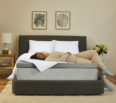 a woman laying on top of a bed next to a white pillow and pillows in a room