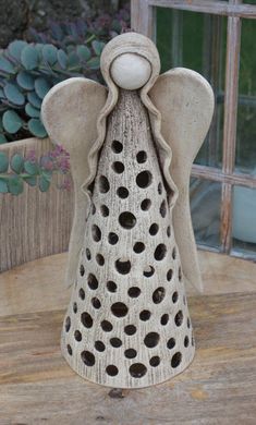 an angel figurine sitting on top of a table next to a potted plant