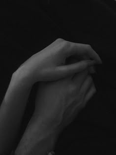 two hands are holding each other in black and white photo, with one hand resting on the other's arm