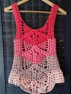 a crocheted tank top hanging on a wooden hanger