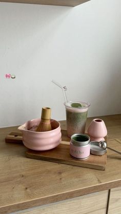 a wooden table topped with pink dishes and cups