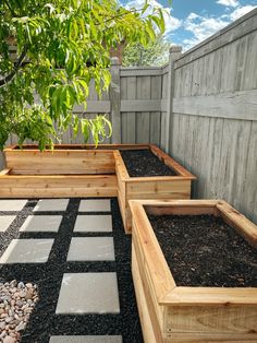 several wooden planters are lined up on the ground in front of a fence and tree