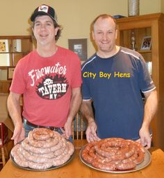 two men standing next to each other holding trays of hot dogs and buns