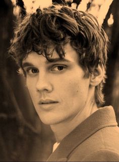 a black and white photo of a young man with curly hair looking at the camera