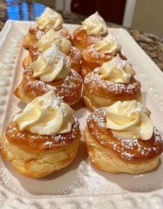 several pastries on a white plate with powdered sugar and icing around them