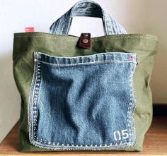 a green bag with a blue jean pocket on it and a red button in the back