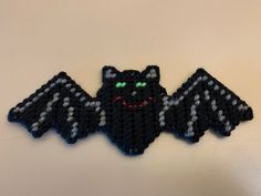 a crocheted bat with green eyes and fangs