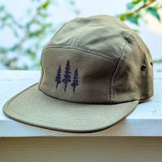 🌲🌲 5% of profits donated to preservation 🌲🌲  Gear up for your next adventure with our olive green tree 5 panel hat, the ultimate camp hat! Crafted from 100% cotton, this hat's flat bill keeps you cool and shaded as you conquer trails, lounge by the campfire, or explore the great outdoors. Your new adventure-ready essential! This hat is olive green with black embroidered trees on the front. Embroidery is custom designed by the shop owner, Alyssa, stitched on front. - 100% cotton - 5 Panel, Camp Hat - Head circumference: 19⅝″-22½″ - Flat Bill - Nylon adjustable strap - Custom embroidery, on the front center - Hand wash, dry flat - Olive green hat - The perfect hiking gift, camping gift and nature gift! Khaki Military Baseball Cap For Outdoor, Military Style Khaki Baseball Cap For Outdoor, Khaki Military Style Baseball Cap For Outdoor, Military Style Khaki Baseball Cap For Outdoor Activities, Military Hat With Flat Bill For Outdoor Activities, Military Snapback Hat For Outdoor, Military Style Snapback Hat For Outdoor, Military Flat Bill Hat For Outdoor Activities, Military Style Baseball Cap With Short Brim