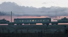 a train traveling down tracks next to a forest filled with trees and power lines at dusk