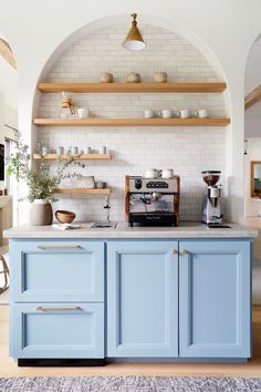 a kitchen with blue cabinets and shelves on the wall