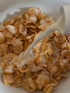 cereal is being poured into a white bowl