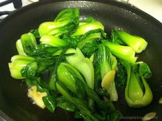 green vegetables are being cooked in a wok on the stove top with some oil