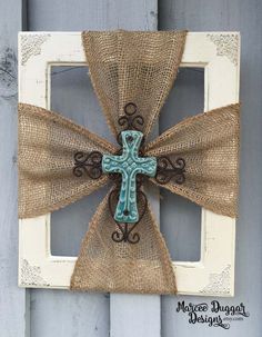 a cross made out of burlock is hanging on a door frame with an old window